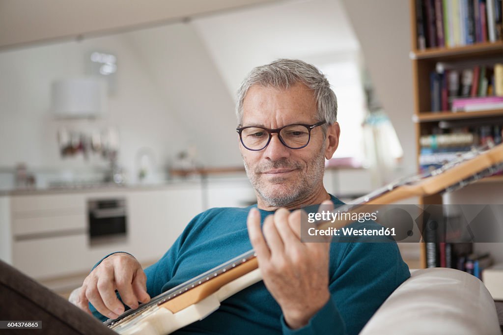 Mature man at home playing guitar