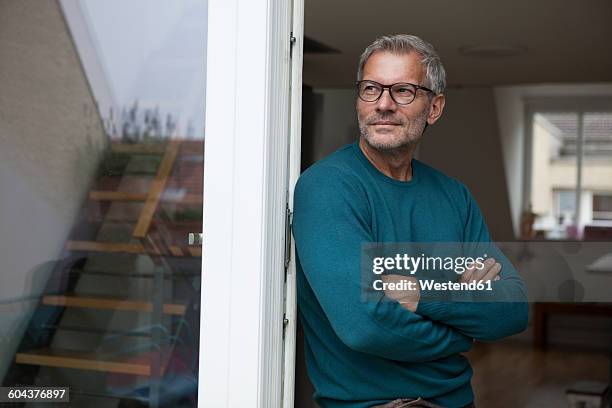 mature man leaning against balcony door - waist up photos et images de collection
