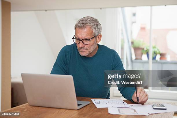 mature man at home using laptop - bavarian man in front of house stock-fotos und bilder