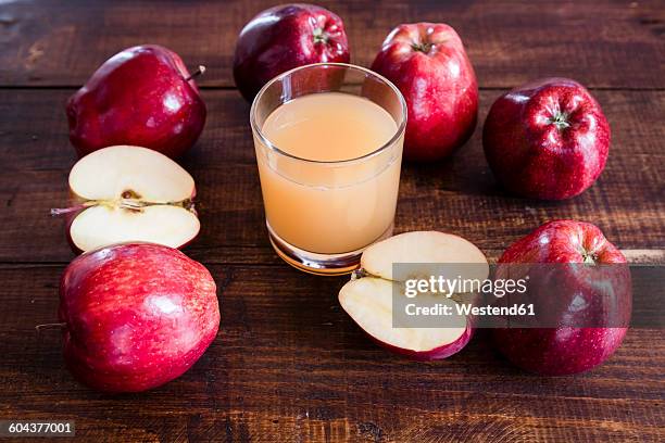 whole and sliced red apples and a glass of apple juice on wood - apple juice stock pictures, royalty-free photos & images