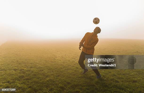 young man playing soccer on meadow in the evening - football field bildbanksfoton och bilder