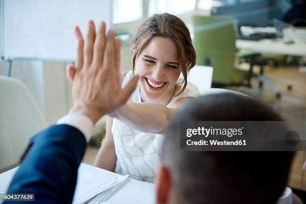 happy businesswoman and businessman high fiving - business people cheering in office stock-fotos und bilder