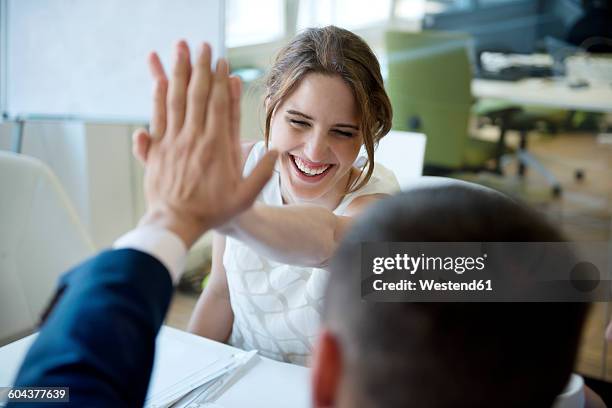 happy businesswoman and businessman high fiving - choque de manos en el aire fotografías e imágenes de stock