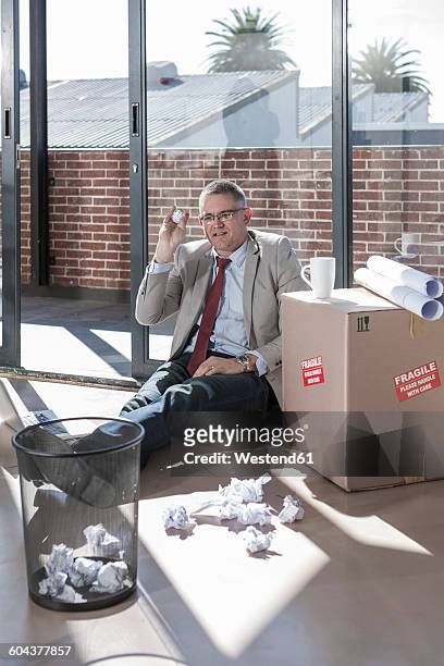 businessman sitting on the floor in a new office throwing crumpled paper - wastepaper basket stock-fotos und bilder