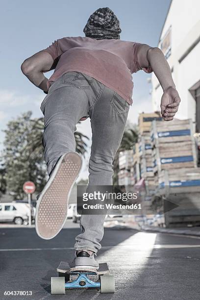 rear view of a skateboarder on the street - minder verzadiging stockfoto's en -beelden