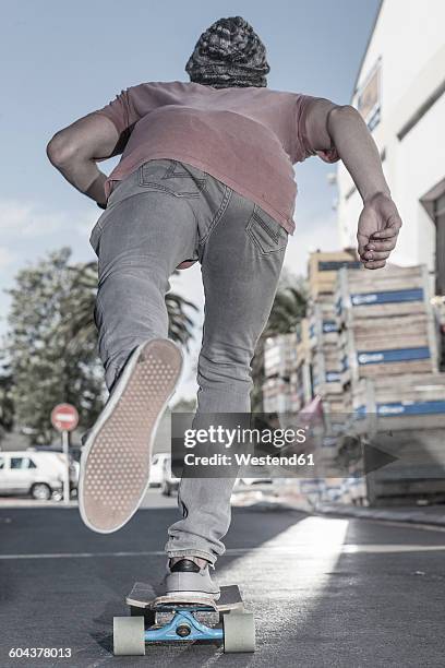 rear view of a skateboarder on the street - single lane road - fotografias e filmes do acervo