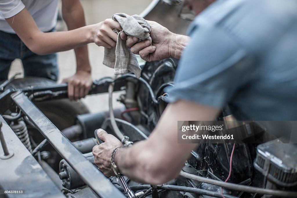 Grandfather and grandson restoring a car together