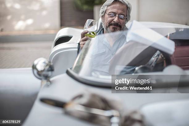 senior man in sports car looking at check list drinking lemonade - drinking soda in car stock pictures, royalty-free photos & images
