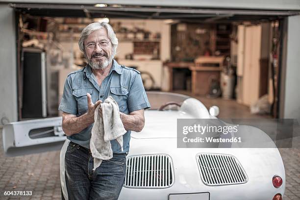 smiling senior man with cleaning cloth leaning at sports car - restaurera bildbanksfoton och bilder