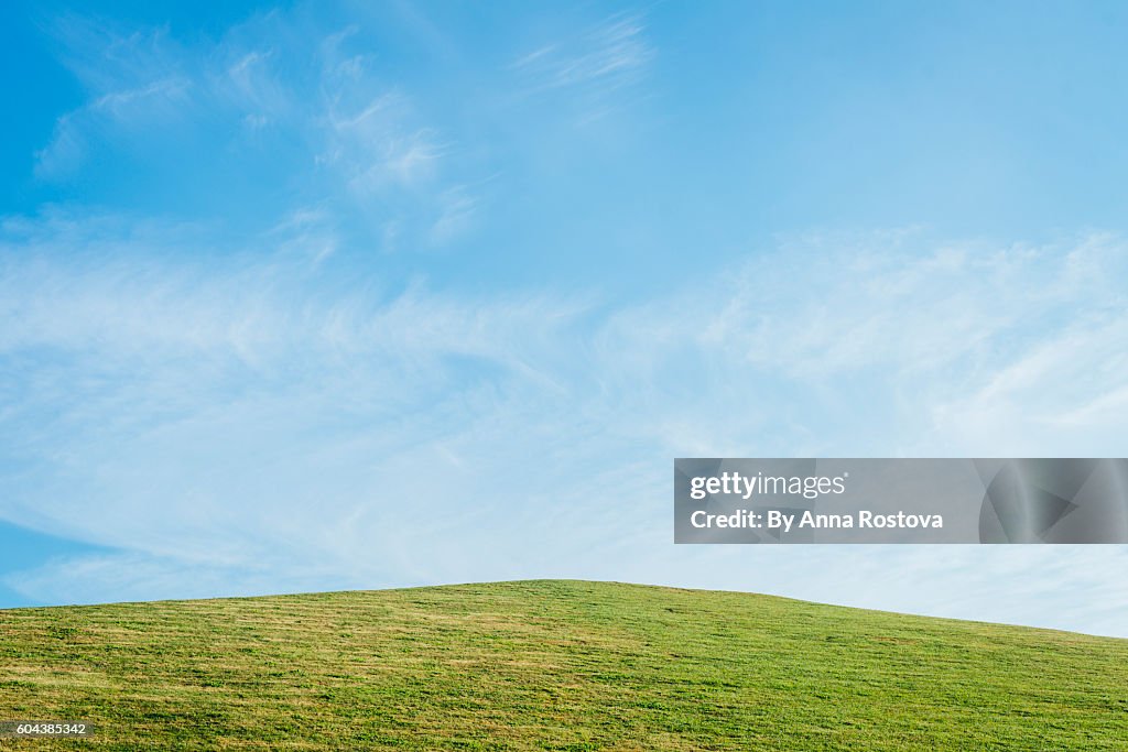 Grassy hill against clear blue sky in summer