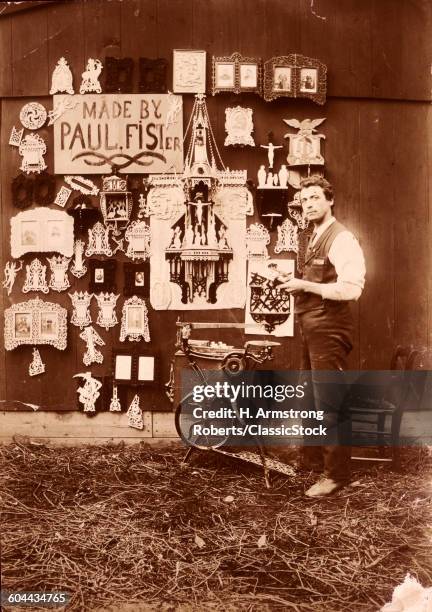 1890s OLD TIME SCROLL SAW SKILLED ARTIST MAN STANDING LOOKING AT CAMERA DISPLAYING WORK AND HIS FOOT POWERED CAST IRON JIGSAW