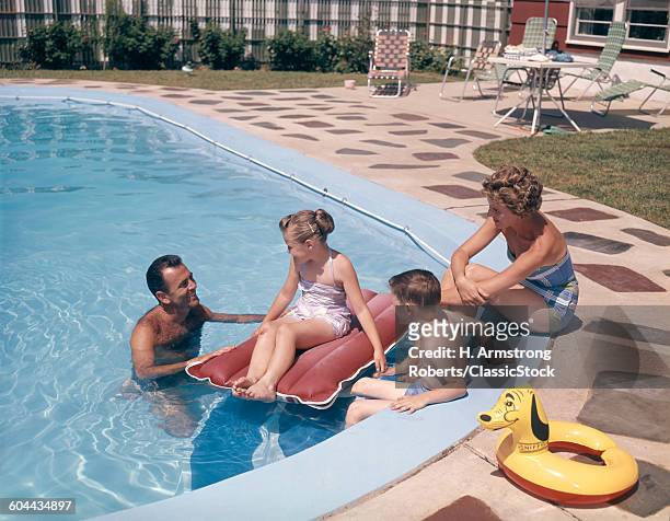 1950s 1960s FAMILY FATHER MOTHER SON DAUGHTER MAN & WOMAN BOY & GIRL TOGETHER IN BACKYARD SWIMMING POOL SMILING
