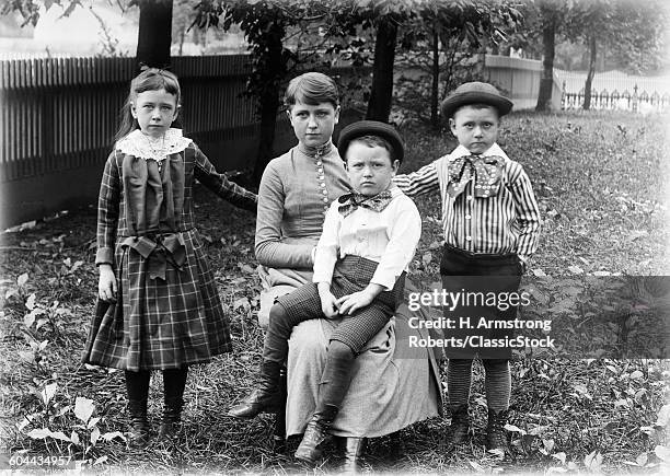 1890s 1900s FAMILY GROUP PORTRAIT SIBLINGS GIRL SISTER TWO BOYS BROTHERS OUTSIDE IN BACKYARD WITH MOTHER LOOKING AT CAMERA