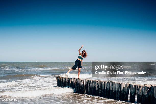 young woman keeping her balance on a pier - ardia stock-fotos und bilder