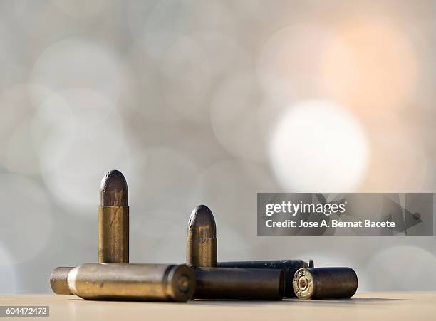 heap of bullets and tips of firearms illuminated by the light of the sun - shooting crime stock pictures, royalty-free photos & images