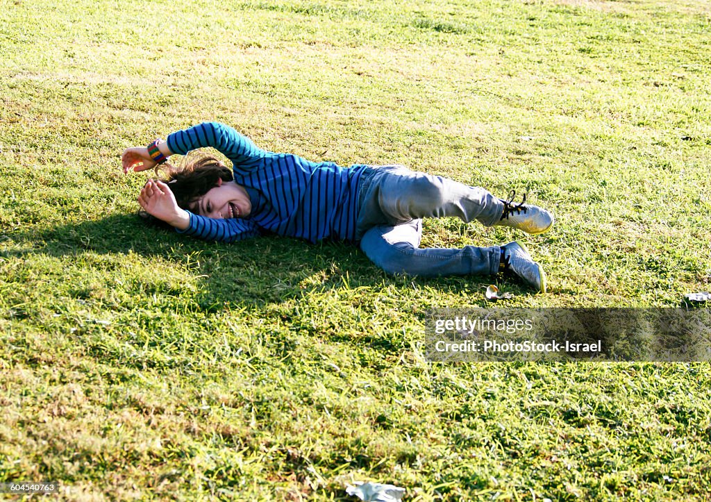 Young boy of six, rolls down a grassy hill