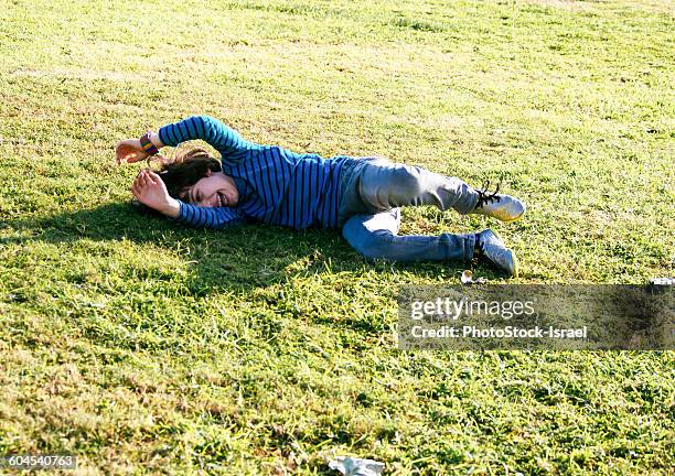 young boy of six, rolls down a grassy hill - roll shirt stock pictures, royalty-free photos & images