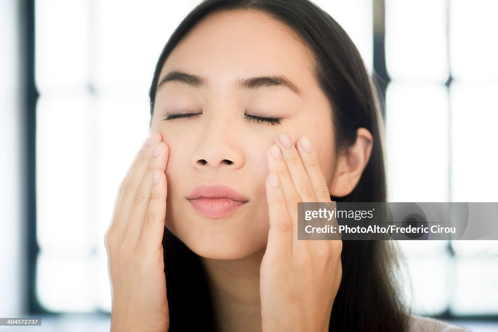 Woman touching her face, eyes closed
