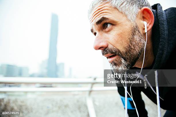 austria, vienna, exhausted athlete wearing earphones - old man close up stockfoto's en -beelden