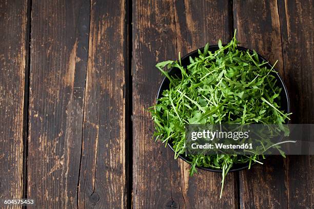 bowl of rocket on dark wood - rucola stock-fotos und bilder