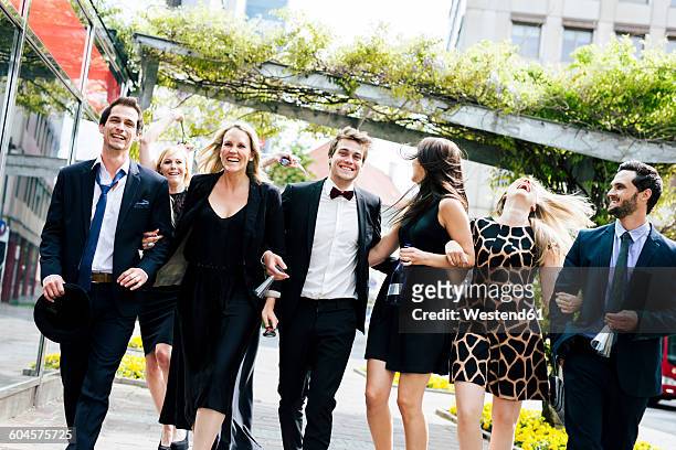 group of well-dressed happy friends walking outdoors - evening gown stock-fotos und bilder