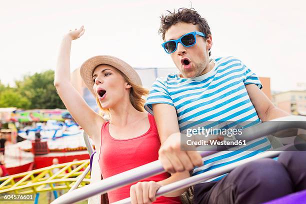 happy couple at fun fair riding roller coaster - rollercoaster stock pictures, royalty-free photos & images