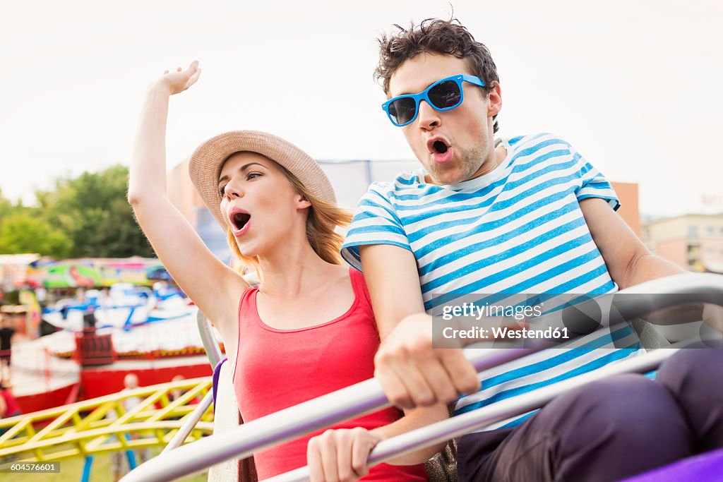 Happy couple at fun fair riding roller coaster