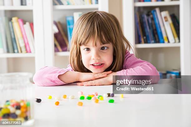 portrait of little girl with jelly beans - cross eyed 個照片及圖片檔