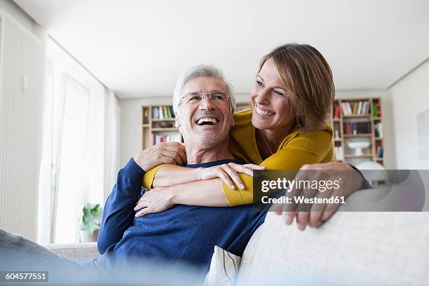 portrait of laughing couple in the living room - mature adult couple stockfoto's en -beelden
