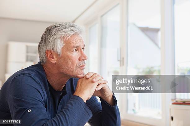 portrait of pensive man at home - ongerust stockfoto's en -beelden