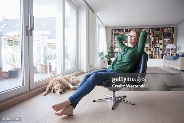 young woman relaxing on a leather armchair at home - barfuß stock-fotos und bilder