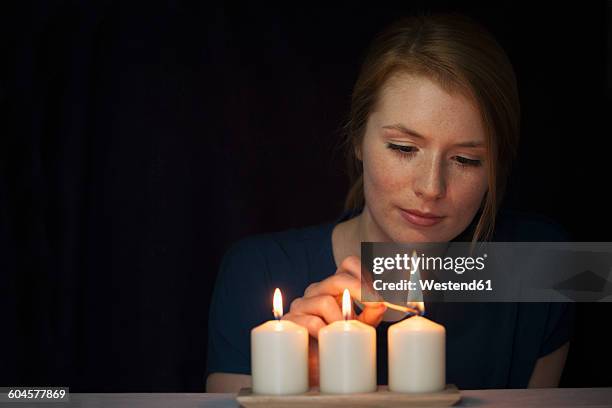 portrait of young woman lighting candles - white candle stock pictures, royalty-free photos & images