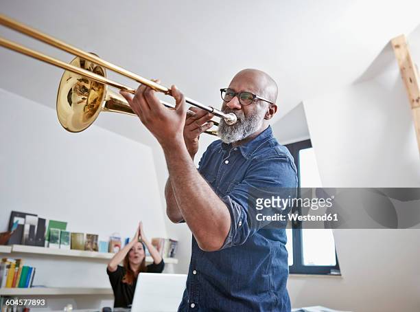 portrait of man playing trombone at home office - trombon bildbanksfoton och bilder