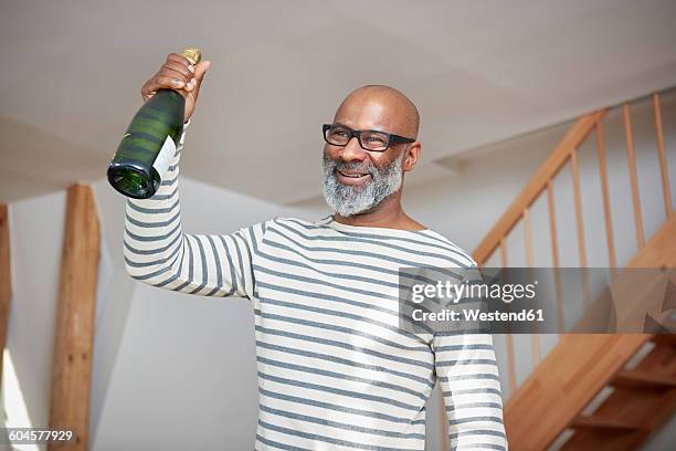 portrait of smiling man holding champagne bottle - cologne bottle stock pictures, royalty-free photos & images