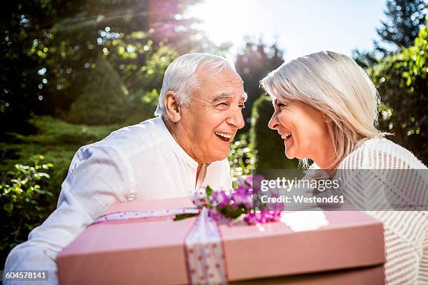 happy elderly couple with large present outdoors - happy anniversary stock-fotos und bilder