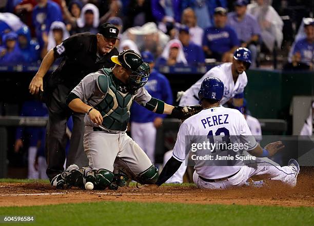 Salvador Perez of the Kansas City Royals slides safely into home to score as catcher Stephen Vogt of the Oakland Athletics drops the ball during the...