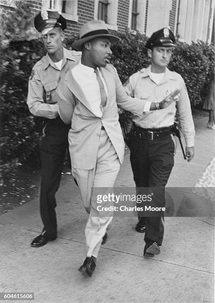 Two police officers escort American religious and Civil Rights leader Dr Martin Luther King Jr away from the Montgomery Recorder's Court where he had...