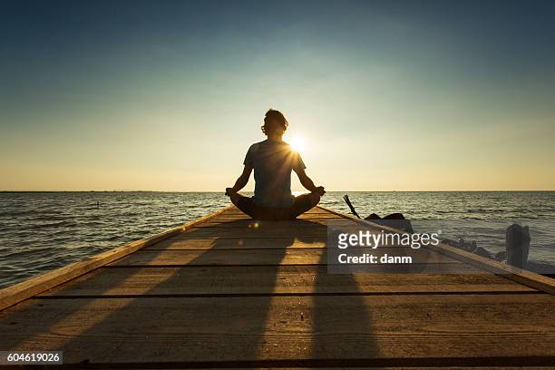 joyful man meditating on pontoon over a lake at sunrise - yoga outdoor foto e immagini stock