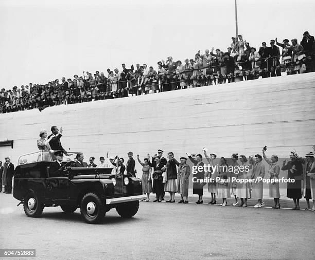 Queen Elizabeth II and Prince Philip, Duke of Edinburgh wave to crowds of spectators from the back of an open top Land Rover car as they drive along...