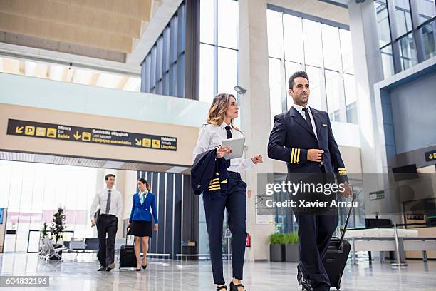 pilots and flight attendants walking at the airport - airhostess stock pictures, royalty-free photos & images