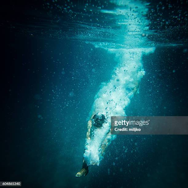underwater action shot of diver breaking water surface - mergulhador imagens e fotografias de stock