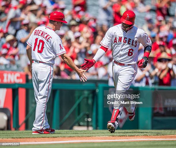 Third base coach Ron Roenicke and Yunel Escobar of the Los Angeles Angels of Anaheim celebrate as Escobar runs the bases after hitting a solo home...