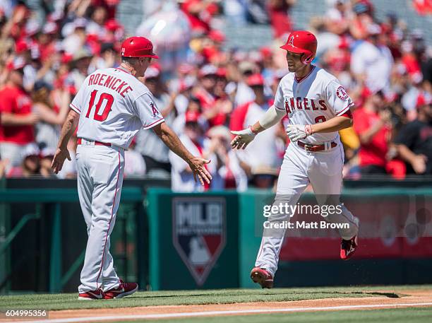 Third base coach Ron Roenicke and Andrelton Simmons of the Los Angeles Angels of Anaheim celebrate as Simmons runs the bases after hitting a solo...