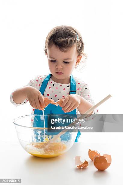 little girl breaking eggs in mixing bowl - crack spoon stock pictures, royalty-free photos & images