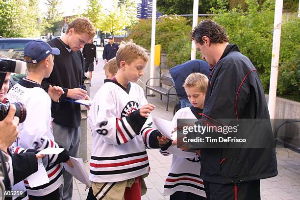 Martin Skoula, left, and Milan Hejduk, of the Colorado Avalanche sign autographs for fans outside their hotel. The Avalanche are in town to...