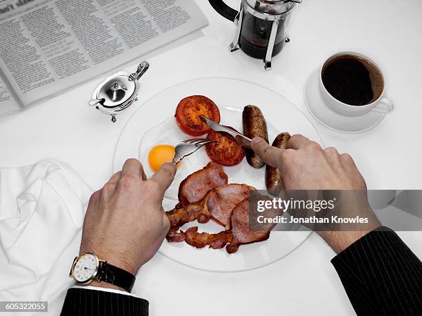 male eating breakfast with newspaper on table - english breakfast stock pictures, royalty-free photos & images