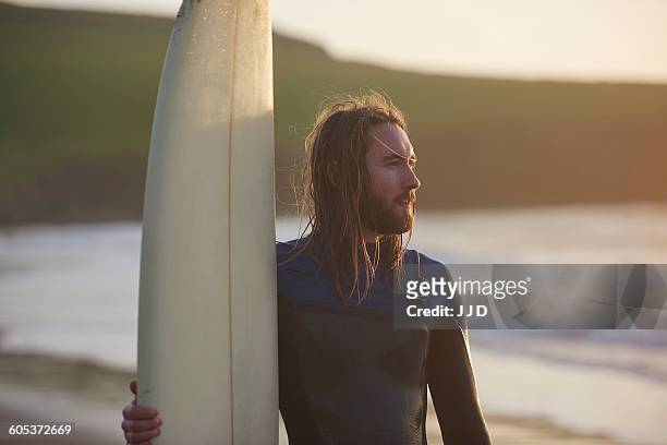 young male surfer at beach, devon, england, uk - beach hold surfboard stock-fotos und bilder