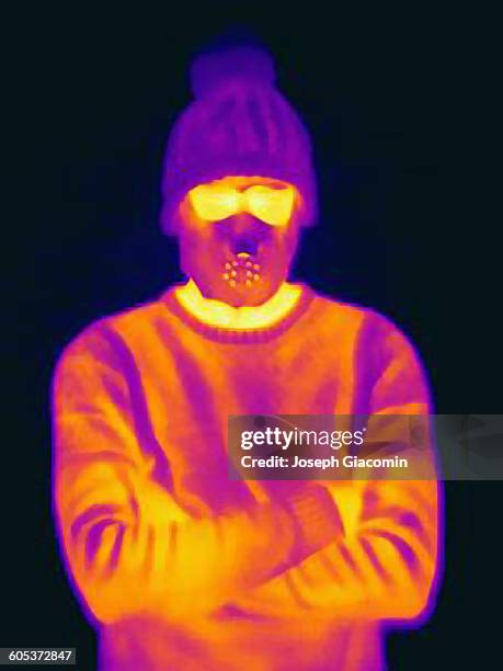 thermal image of man with crossed arms wearing threatening mask and knit hat - image infrarouge photos et images de collection