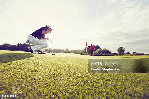 golfer crouching on course, korschenbroich, dusseldorf, germany - course caddie stock pictures, royalty-free photos & images