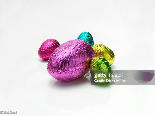 colourful easter eggs in shiny foil on white background - huevo de pascua de chocolate fotografías e imágenes de stock